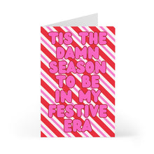 Load image into Gallery viewer, Check out the "Tis the Damn Season Festive Era Christmas Card" by R is for Robo, featuring a red and white diagonal striped background with bold pink text that reads "'Tis the damn season to be in my festive era." This humorous Taylor Swift-themed card is perfect for Swifties and guaranteed to spread holiday cheer!