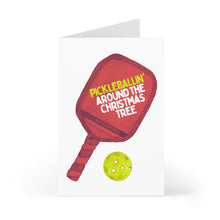 Load image into Gallery viewer, The Pickleball Christmas Card by R is for Robo features a red paddle next to a green ball, adorned with the festive phrase "Pickleballin Around the Christmas Tree." Designed for Pickleball Lovers, it makes an ideal addition to your collection of Pickleball Gifts. The simple white background adds to its appeal.