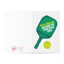 Load image into Gallery viewer, The Pickleball Christmas Card, perfect for pickleball enthusiasts, features a green paddle and the phrase "Pickleballin Around the Christmas Tree" next to a yellow pickleball. This festive card by R is for Robo opens to reveal brand information and contact details, making it an ideal holiday gift.
