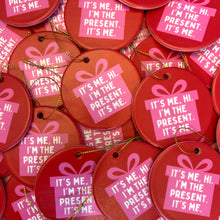 Load image into Gallery viewer, A collection of slightly imperfect holiday ornaments from R is for Robo, called Oops Seconds Christmas Ornaments, showcase red ceramic treasures featuring a pink gift icon and the phrase "It's me. Hi. I'm the present. It's me." Complete with gold strings for hanging.