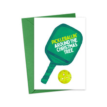 Load image into Gallery viewer, Introducing the Pickleball Christmas Card by R is for Robo, designed for pickleball enthusiasts. This delightful card showcases a green paddle and a yellow pickleball alongside the phrase "PICKLEBALLIN' AROUND THE CHRISTMAS TREE" in white letters. It comes complete with a matching green envelope, making it an ideal unique gift for any fan of the sport!