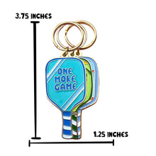 Load image into Gallery viewer, Introducing the Pickleball Paddle Enamel Keychain by R is for Robo, a perfect gift for pickleball enthusiasts. This keychain showcases a stack of vibrant, paddle-shaped tags with the front tag in blue featuring the text "One More Game." Measuring 3.75 inches tall and 1.25 inches wide, it's an ideal way to keep your passion close at hand.