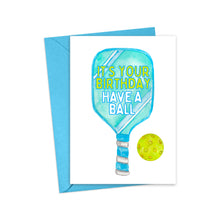 Load image into Gallery viewer, Celebrate a pickleball lover's birthday with the R is for Robo Pickleball Birthday Card. This funny card features a vibrant blue paddle and a yellow ball, with the text "It's Your Birthday, Have A Ball" displayed on the paddle. Ideal for pickleball gifts, it comes with an open blue envelope ready to share smiles and laughter.