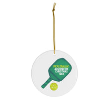 Load image into Gallery viewer, The "Pickle Ball Christmas Christmas Ornament" by R is for Robo is a charming ceramic holiday decoration, showcasing a pickleball paddle and ball design. The paddle includes the inscription "Pickleballin Around the Christmas Tree," and it elegantly hangs from a gold string, making it an ideal addition to your festive decor.