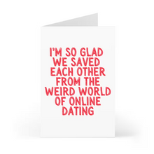 Load image into Gallery viewer, Capture the essence of your unique love story with this charming anniversary card from R is for Robo. Featuring bold red text on a white background, it reads, "IM SO GLAD WE SAVED EACH OTHER FROM THE WEIRD WORLD OF ONLINE DATING." This delightful card stands upright against a simple backdrop, making it perfect for expressing sentiment on a special occasion.