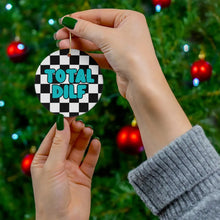 Load image into Gallery viewer, Hands holding the DILF Christmas Ornament - Gift for Hot Dad from R is for Robo, featuring a black and white checkered pattern with bold blue letters spelling TOTAL DILF. In the background, a Christmas tree adorned with red baubles adds festive cheer to this humorous piece of holiday decor.