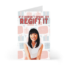 Load image into Gallery viewer, The "Spark Joy Funny Christmas Card" by R is for Robo features a delightful design of a smiling woman surrounded by gift boxes, with a handwritten note above stating, "If it doesn't spark joy, regift it.
