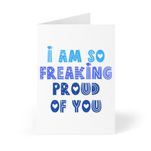 Load image into Gallery viewer, The "I am So Freaking Proud Congratulations Card" by R is for Robo is a heavyweight matte card adorned with the statement "I am so freaking proud of you" in bold, decorative blue fonts and heart designs. It stands open at a slight angle on a white background, providing the ideal space for your heartfelt handwritten note.
