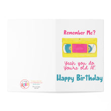 Load image into Gallery viewer, The 90s Retro Neon You're Old AF Funny Birthday Card by R is for Robo showcases a hand-drawn VHS tape with "Remember Me?" above it. The card humorously continues with "Yeah, you do. You're old AF" in retro neon pink and concludes with "Happy Birthday" in blue, making it an ideal gift for 90s nostalgia lovers. The brand's logo is positioned on the left side.