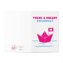 Load image into Gallery viewer, A delightful Valentine's Day card called "Cute Valentines Day Card for Husband or Wife" from R is for Robo showcases a pink paper boat with a heart flag sailing on blue waves. The whimsical message reads, "You're a dreamy dreamboat." To add a personal touch, there's space for a handwritten note, while branding and the website details are elegantly placed in the bottom left corner.