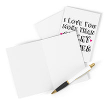 Load image into Gallery viewer, A blank greeting card and envelope rest beside the Chicky Nuggies Chicken Nuggets Anniversary Card by R is for Robo, featuring the message "I love you more than Lucky Charms" in black letters with pink hearts. Nearby, a black and white pen with gold accents awaits your heartfelt handwritten note.