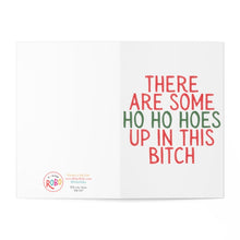 Load image into Gallery viewer, The "Ho Ho Hoes Funny Christmas Card" by R is for Robo features the humorous text "There are some ho ho hoes up in this bitch" in festive red and green letters. It is printed on heavyweight matte card with a white background and has a small logo at the bottom left corner, making it perfect for adding a handwritten note.