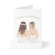 Load image into Gallery viewer, The "Two Brides Wedding Card" by R is for Robo features an illustration of two brides in wedding dresses, viewed from behind on a heavyweight matte card. One bride has dark, wavy hair with a floral headband, while the other has straight, blonde hair. The card displays the text "Two brides are better than one" against a white background, making it an ideal choice for celebrating a lesbian wedding.