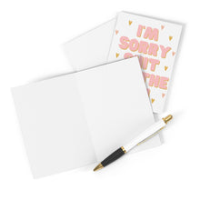Load image into Gallery viewer, On a white surface lies the "Shit Hit the Fan Funny Sympathy Card" by R is for Robo, featuring one heavyweight matte card opened with blank pages and another closed, showcasing "I'm Sorry" in pink lettering accompanied by small orange hearts. A black and white pen with a gold accent rests on the card, ready for your personal message.