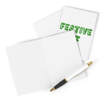 Load image into Gallery viewer, Two blank greeting cards from R is for Robo, with one showcasing "Festive AF" in green letters, embody the essence of holiday cheer. Adjacent is a black and white pen adorned with gold accents. All these items are set on a clean, white surface, making them ideal as the perfect Festive AF Funny Christmas Card for someone special.