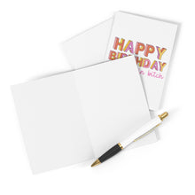 Load image into Gallery viewer, The "Main Bitch Birthday Card" by R is for Robo, features vibrant "Happy Birthday" lettering with an expletive underneath. It's partially open next to a blank white card accompanied by a black and white pen, perfect for adding your personal touch.