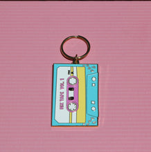 Load image into Gallery viewer, Introducing the Cassette Tape Keychain by R is for Robo, a delightful throwback for any 90s kid. This charm features a retro cassette shape in soft pastel shades of blue, pink, and yellow. The design proudly showcases "Mix Tape Vol. 1" against a textured pink background, capturing the essence of vintage flair perfectly.