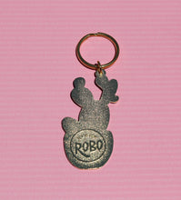 Load image into Gallery viewer, A silver keychain, shaped like a cactus with "R is for Robo" engraved on it, gleams against a pink background, making it the perfect accessory for any dedicated plant mom.