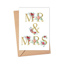 Load image into Gallery viewer, A heavyweight matte card from R is for Robo, featuring the text MRS & MRS in shimmering gold and adorned with floral designs in shades of red and pink, elegantly rests on a kraft envelope. This charming Mrs and Mrs Wedding Card captures a timeless elegance.