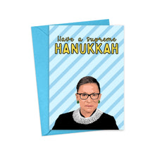 Load image into Gallery viewer, The RBG Ruth Bader Ginsburg Hanukkah Card from R is for Robo showcases a woman in a black robe and lace collar. It features the text "Have a supreme Hanukkah" on a striking blue striped background, finished with heavyweight matte cardstock and paired with a matching blue envelope.