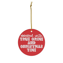 Load image into Gallery viewer, The True Crime Funny Christmas Ornament by R is for Robo is a round, red ceramic ornament featuring the phrase "Obsessed with true crime and Christmas time" in bold white letters, complete with a golden string—an ideal humorous gift for the true crime enthusiast in your life.