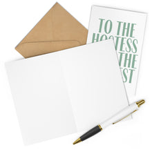 Load image into Gallery viewer, A blank card from R is for Robo, paired with a gold and white pen, lies open on a flat surface—ideal for composing a heartfelt note. Beside it stands an envelope behind the folded heavyweight matte "Hostess with the Mostest Thank You Card," adorned with green text.