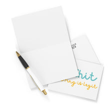 Load image into Gallery viewer, An open "That Ring is Legit" engagement card by R is for Robo reveals the phrase in teal and orange, with another card partially visible beneath. A white pen with gold accents is placed diagonally across this humorous engagement card, ideal for a bride-to-be. The background features a plain white surface.