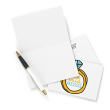 Load image into Gallery viewer, An elegant engagement card from R is for Robo's "She Said Yas Funny Engagement Card" collection lies open next to a white pen with a gold tip. Beneath it, a smaller card features a vibrant illustration of an engagement ring with "She said YASSSSSS" inside, creating the perfect setting for jotting down your heartfelt handwritten note.