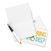 Load image into Gallery viewer, Bird's-eye view of an open blank engagement card, a black and gold pen, and the New Ring Who Dis Funny Engagement Card by R is for Robo, featuring a drawing of a ring with the text "Who dis?" Ideal for adding your personal touch or a hand-written note.