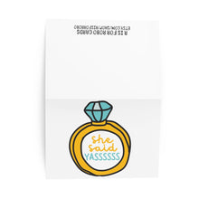 Load image into Gallery viewer, This "She Said Yas Funny Engagement Card" by R is for Robo highlights a gold ring with a blue diamond and playful text in vibrant yellow and teal that reads "she said YASSSSS." The card, ideal for celebrating love, is partially opened against a white background, ready for your own heartfelt handwritten note.