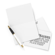 Load image into Gallery viewer, A heavyweight matte piece of paper lays on a white surface alongside a black and white pen, next to the "So Jealous Funny Going Away Card" by R is for Robo, partially visible with bold text reading LEAVE THIS GOD FORSAKEN PLACE FIRST.
