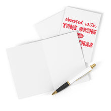 Load image into Gallery viewer, A blank greeting card and envelope lie next to a pen. Another card with red text from R is for Robo reads "obsessed with true crime and Christmas"—it's the perfect True Crime Murder Podcast Christmas Card for those who revel in Festive Fear during the holidays.