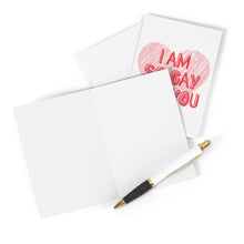 Load image into Gallery viewer, An elegant matte card lies open, accompanied by a pen poised for a handwritten note. Beside it is the LGBTQ Funny Anniversary Card from R is for Robo, featuring a large pink heart and bold red letters proclaiming, "I am so gay for you.
