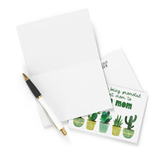 Load image into Gallery viewer, An open blank greeting card sits beside a black and white pen, while an envelope features the R is for Robo heavyweight matte "Plant Mom Funny New Baby Card." This card is adorned with green text and playful potted cacti illustrations, making it ideal for celebrating new beginnings or writing a heartfelt note.