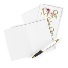 Load image into Gallery viewer, A Mr and Mr Wedding Card by R is for Robo, featuring a heavyweight matte finish with an elegant gold and floral design, is displayed. A black and white pen adorned with gold accents sits poised on the open card, ready for your handwritten message. This sophisticated scene unfolds against a simple white background.