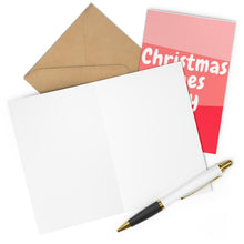 Load image into Gallery viewer, The scene displays an open blank greeting card accompanied by a brown envelope and a pen, alongside a closed red card emblazoned with "Christmas Wishes," all set against a pink background. Experience the holiday joy with the "Christmas Vibes Only - Modern Funny Christmas Card" by R is for Robo, ideal for sending heartfelt greetings to loved ones this season.