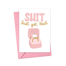 Load image into Gallery viewer, The "Shit Just Got Real Funny Engagement Card" by R is for Robo features a luxurious pink and gold envelope with bold lettering that says SHIT just got REAL. Complementing the text, an illustration of an engagement ring is elegantly displayed in an open pink box, ready to dazzle.