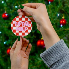 Load image into Gallery viewer, Two hands hold a playful ornament labeled with the bold pink text TOTAL MILF in a red and white checkered pattern. The MILF Christmas Ornament by R is for Robo makes for a humorous holiday decoration, complemented by a backdrop of a Christmas tree adorned with red baubles.
