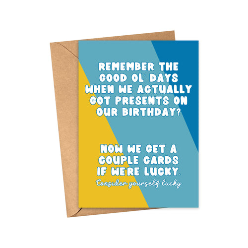 The Funny and Sassy Birthday Card for Men or Women by R is for Robo features a blue, yellow, and teal geometric background. It humorously states, Remember when we got presents on our birthday? Now we’re lucky with a couple cards. Consider yourself lucky. Comes with a brown envelope.